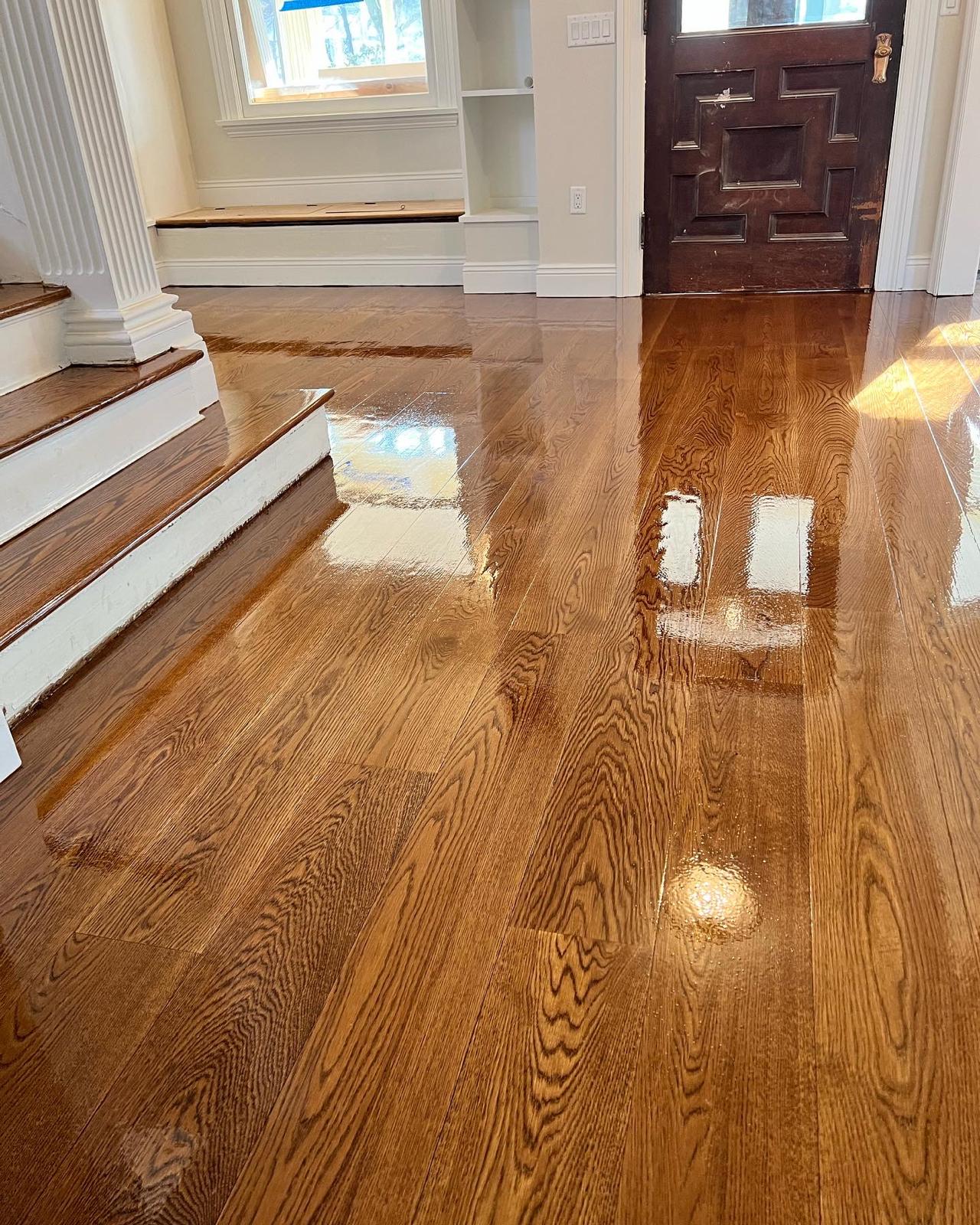 Glossy refinished hardwood floor near a staircase and front door