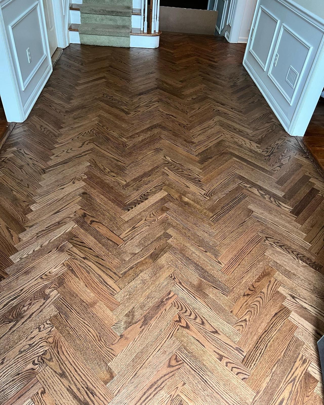 Dark stained herringbone hardwood floor near a staircase